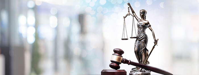 Statue of blind Justice holding scales next to a judge's gavel