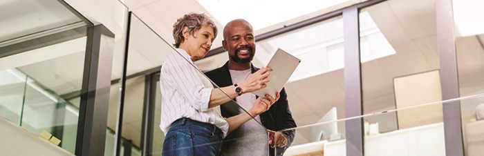 Woman and man looking at a tablet in an office hallway